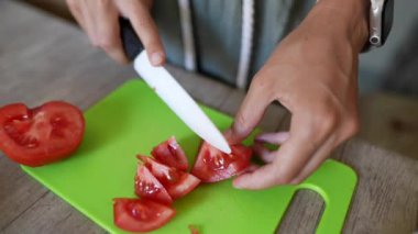 Mutfaktaki ellerde yakın plan çekimler yeşil domatesleri bıçakla doğrayıp, canlı bir sahne yaratıyor.