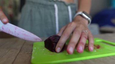 Beyaz bir bıçakla pancarı doğrayan, pancar kökünü kesen ellerin yakın çekimi..