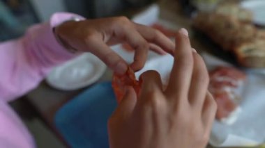 Arka planda çeşitli lezzetli malzemelerle mutfak tezgahında yemek hazırlayan ellerin yakın çekimi..