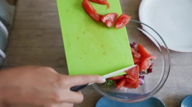Domatesleri yeşil kesim tahtasıyla doğrayıp bir kase taze salata malzemesi eklemek.