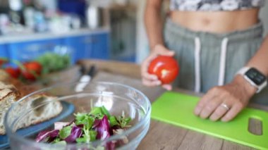 Sıcak mutfakta taze sebzeler ve salata malzemeleriyle sağlıklı bir yemek hazırlayan kişi..