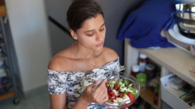 Besin paketlenmiş bir salata, genç bir bayan tarafından sıcak bir mutfakta, sağlıklı bir yaşam tarzının somutlaştırılması fikri ile tatlandırılıyor.