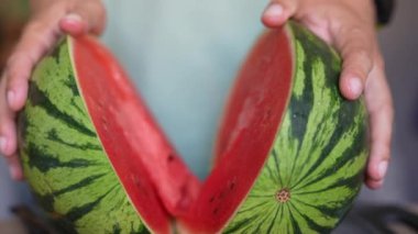 Taze dilimlenmiş karpuz, canlı kırmızı ve sulu eller, nefis bir yaz atıştırması.
