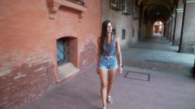 Genç bir kadın renkli duvarları ve canlı dokuları olan büyüleyici bir sokak arasında dolaşır.