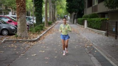 Genç bir kadın hareketli bir şehir kaldırımında hareketli şehir yaşam tarzını somutlaştırarak rahatça yürüyor.