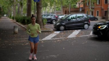 Genç bir kadın zarif bir şekilde ağaçlarla dolu huzurlu ve huzurlu bir sokakta yürüyor.