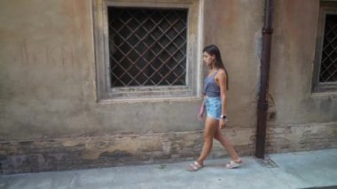 Genç bir kadın zarif bir şekilde eski bir caddede yürüyor, özgürlük ve eşsiz bir stili somutlaştırıyor.