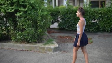 Genç bir kadın, çevresini canlı ve yemyeşil saran sakin bir ortamda rahatça dolaşır.