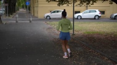 Yeşil ağaçlarla çevrili manzaralı bir yolda neşeyle koşan bir insan aktif ve sağlıklı bir yaşam tarzı sergiliyor.