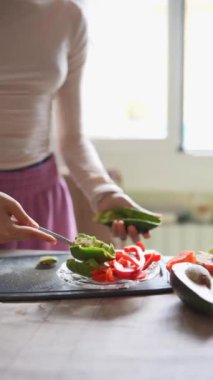 Bir kadın parlak ve davetkar bir mutfak ortamında çeşitli taze sebzeler hazırlıyor.