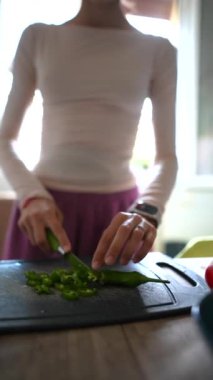 Bir insan, parlak ve davetkar bir mutfak ortamında ahşap bir kesme tahtasında ustalıkla taze otları doğruyor.