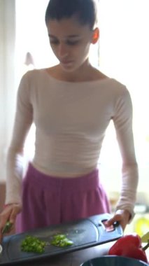 Sıcak bir mutfakta, bir kadın sağlıklı pişirme tekniklerine odaklanmak için bir dizi taze sebzeyi ustalıkla hazırlıyor.