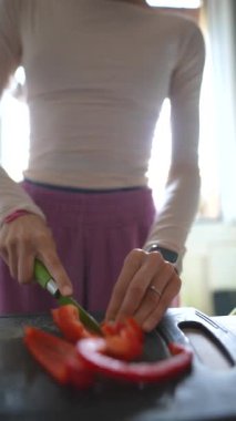 Parlak bir mutfakta rengarenk sebzeleri ustalıkla dilimleyen bir insan sağlıklı yemek pişirmenin özünü yakalar..