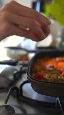 Lezzetli bir yemek hazırlığı yapılıyor, taze malzemeler sergileniyor ve yemeğe bir yumurta ekleniyor.