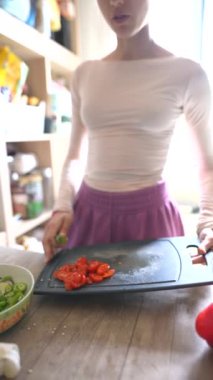 Genç bir şef taze domatesleri ustalıkla doğrar, canlı bir mutfakta sağlıklı yemek yapmanın önemini vurgular.