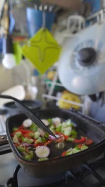 Canlı ve renkli bir taze sebze karışımı modern bir mutfak ortamında ustalıkla karıştırılıyor.