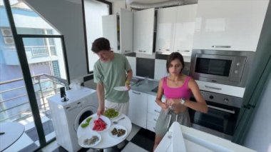 Bir çift, şık ve modern bir mutfakta, taze malzemelerle birlikte lezzetli yemekler pişiriyor.