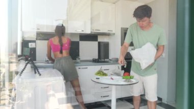 Genç bir çift modern bir mutfakta taze malzemeler hazırlıyor. Lezzetli bir yemek yaratmak için takım çalışması yapıyorlar.