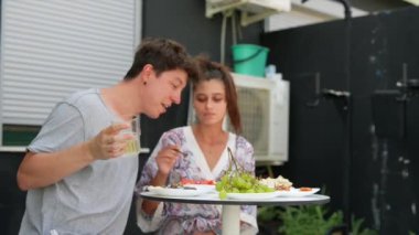 Açık havada yemek yiyen genç bir çift, o anın tadını ve bağlantılarını vurguluyor.