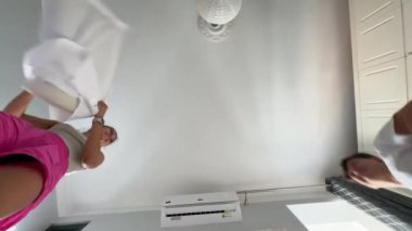 İki kadın rahat ve rahat bir ortamda, mutlu bir şekilde çamaşır katlıyor ve birlikte yaşam alanlarını düzenliyorlar.