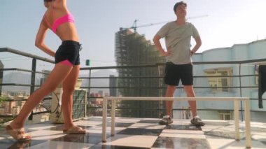 Güneşli bir günde, iki yakın arkadaş çatıdaki terasta eğlenceli aktivitelerin keyfini çıkararak harika anılar yaratırlar.