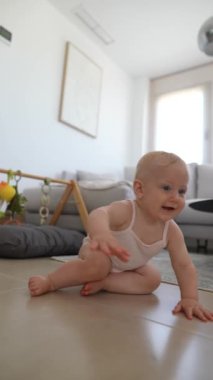 Neşeli bir bebek şık bir oturma odasının zemininde oturur, etrafını büyük bir zevkle keşfeder.