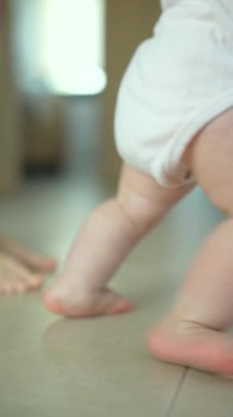 Yürümeye yeni başlayan bir çocuk ilk adımlarını atar ve erken yürümenin verdiği keyfi gösterir. Düşük bir perspektiften çekilmiş.