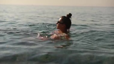 Sakin bir an, sakin okyanus sularında süzülen yalnız bir yüzücünün çarpıcı bir günbatımında güzel bir görüntüsü.