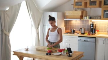 Bir kadın besleyici bir yemek için parlak ve modern bir mutfakta çeşitli taze sebzeler hazırlıyor.