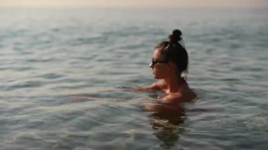 Bir kadın, güzel bir günbatımında sakin sularda neşe keşfeder. Doğanın zarif cazibesini sergiler.