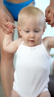 Sevecen bir çocuk ilk adımlarını atıyor. Sevecen ve şefkatli bir ebeveyn tarafından destekleniyor.