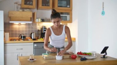 Bir kadın modern mutfağında sağlıklı bir yemek hazırlar. Taze ve renkli malzemeler sergiler.