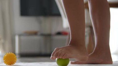 Genç bir çocuk, evde renkli oyuncaklarla hevesle oynarken, neşeyle yumuşak yeşil bir topa basar.