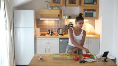 Genç bir birey şık bir mutfak ortamında taze ve canlı sebzeler hazırlar.