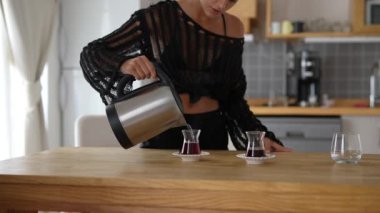 Keyifli bir insan zarif bardaklara aromatik kahve döker, sıcak bir mutfağın tadını çıkarır.