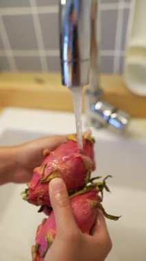 Taze bir ejderha meyvesi lavaboda yıkanır, canlı renklerini ve eşsiz dokusunu sergiler, çekici görünür.