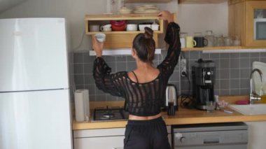 Bir kadın, modern mutfak atmosferinde mutfak malzemelerine zahmetsizce uzanıyor.