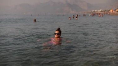 Gün batımında sakin deniz manzarasından gerçekten zevk alan bir kadının oynadığı güzel ve huzurlu bir sahil sahnesi.
