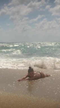 Neşeli bir çocuk kumsalda güneşli bir günün tadını çıkartıyor, yumuşak dalgalar ve yumuşak kumlarla oynuyor.