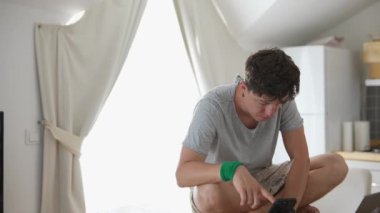 Genç bir adam, güneşli bir mutfakta yemek pişirmekle meşgul. Rahatlamış bir sabah atmosferini somutlaştırıyor.