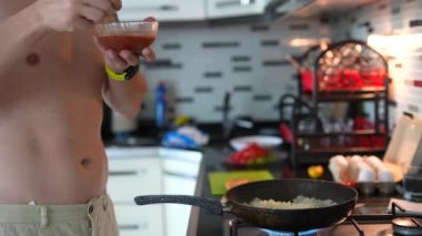 Tutkulu bir insan şık bir mutfakta zevkle yemek pişirir sosları ustalıkla karıştırır ve lezzetli yemekler hazırlar.