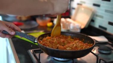 Modern bir fırının tepsisindeki lezzetli malzemeleri karıştıran bir el ev yemeğinin özünü yakalıyor..