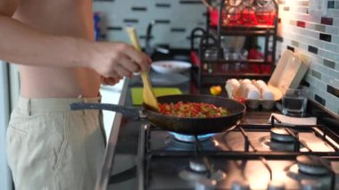 Modern, çağdaş bir mutfak ortamında coşkulu ve renkli bir kızartma pişiren bir insan.