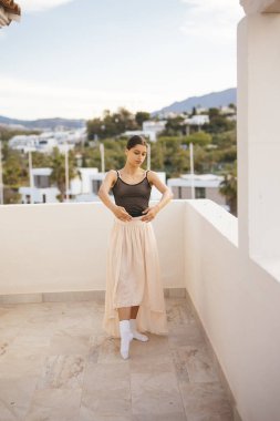 Bir dansçı güneşli bir balkonda zarifçe poz verir zarafetini, güzelliğini ve zarafetini gösterir.