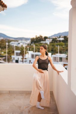 Doğayla iç içe olan, balkonda etekli bir modelin sakin bir anı, güzel bir sahne yaratıyor.