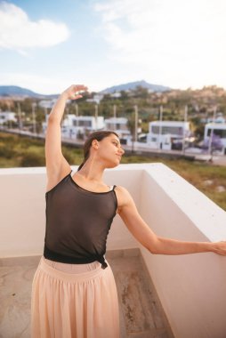 Yetenekli bir dansçı balkonda güzel bir poz verir, zarafeti doğal güzelliğiyle harmanlar.