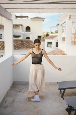 Dalgalı kıyafetli zarif bir dansçı büyüleyici mimarisi olan güzel bir balkonda ustalıkla gösteri yapar.