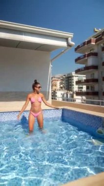 Bir kadın mutlu mesut güneşli bir günün tadını çıkarıyor. Çatı katındaki bir havuzda, yazın ve boş zamanların neşesini somutlaştırıyor.