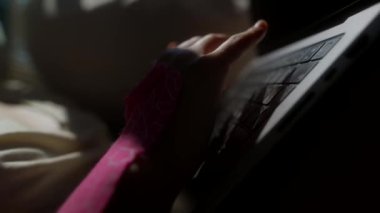 Bir el, modern çalışma alışkanlıklarını ve yaşam tarzını yansıtan yumuşak ışıklı bir alanda dizüstü bilgisayarla ustalıkla etkileşir.