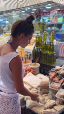 Bir kadın canlı, hareketli, taze ürünler ve çeşitli lezzetlerle dolu bir pazarda sanatsal ürünlere göz atıyor.